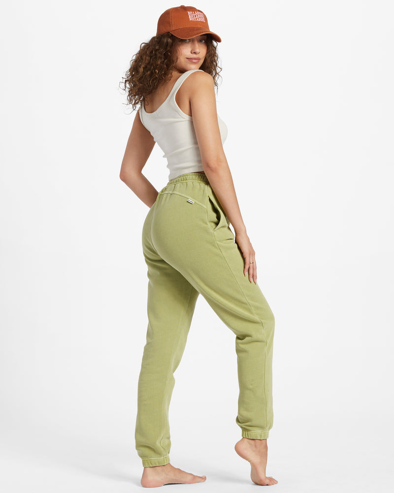 Side view of the model wearing the sunset joggers in avocado. shows the on seam pockets. also shows the elastic ankles, and the seaming on the side and not the back side. 