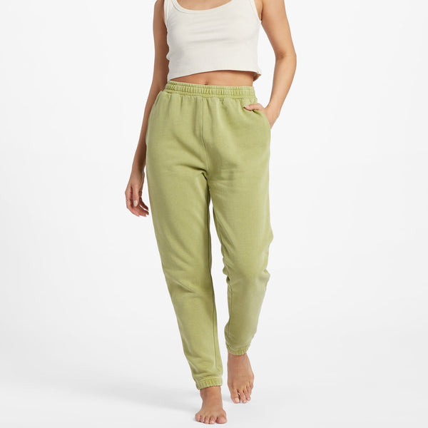 front view of the model wearing the sunset joggers in the color avocado. shows the elastic waistband. also shows the high waist, the elastic ankles and the on seam pockets.