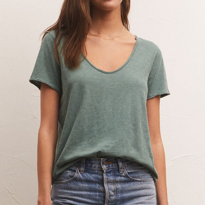 shows front view of model in green tee. shows the low scoop neckline and loose fit.