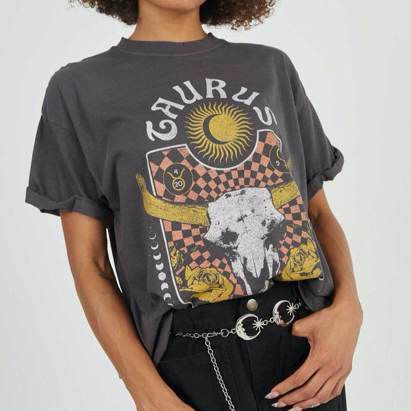Front view of model wearing tee. Shows the crew neckline. Also shows the cuff sleeves, distressing on neckline and the taurus zodiac graphic. 