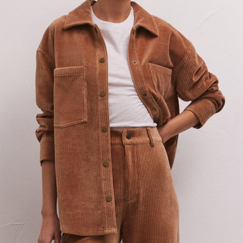 front view of model wearing the union cord jacket in camel. shows the collar. also shows the button down closure, the oversized chest pockets and the ribbed, corduroy detail. 