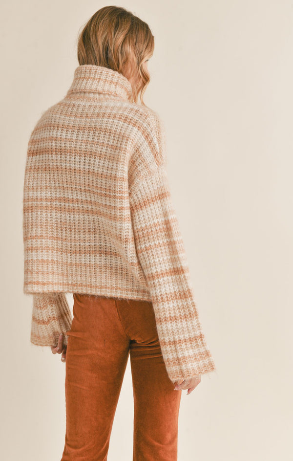 back view of model wearing Loretta turtleneck sweater in cream multi. shows the striping detail throughout. also shows the drop shoulders, the oversized fit and the wide sleeves. 
