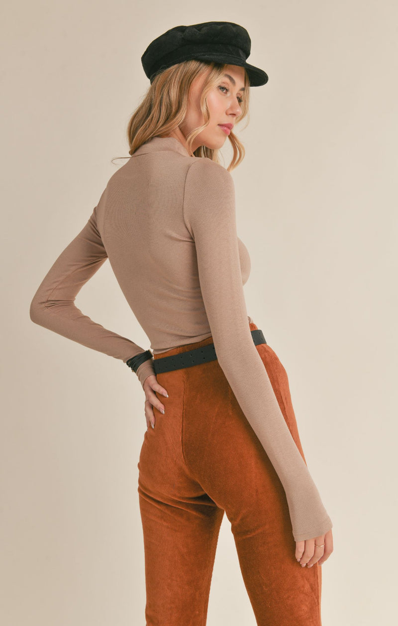 back/side view the Ronan top in taupe. shows the ribbed detail throughout. also shows the mock neck, the defined seams and the thumbholes.
