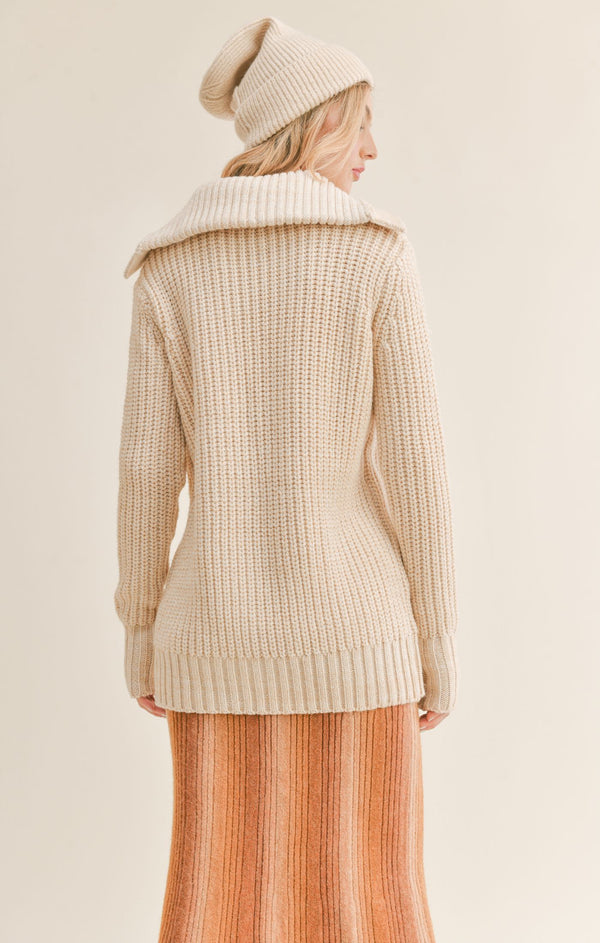 Back view of model wearing the cardigan. Shows the back of the wide collar. Also shows the long sleeves  and the knit sweater material. 