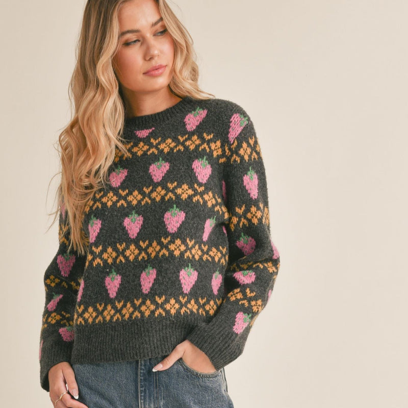 front view of the model wearing the berry sweet sweater. shows the ribbed detail on the neckline, cuffs and hem. also shows the cute strawberry pattern, the crew neckline and boxy fit. 