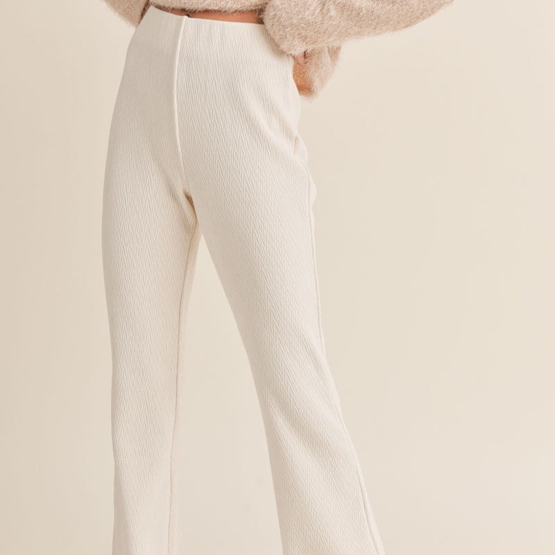 front view of the model wearing the mountain air flair pants in ivory. shows the high waist. also shows the elastic waist band, the pull on style and the defined seams. 