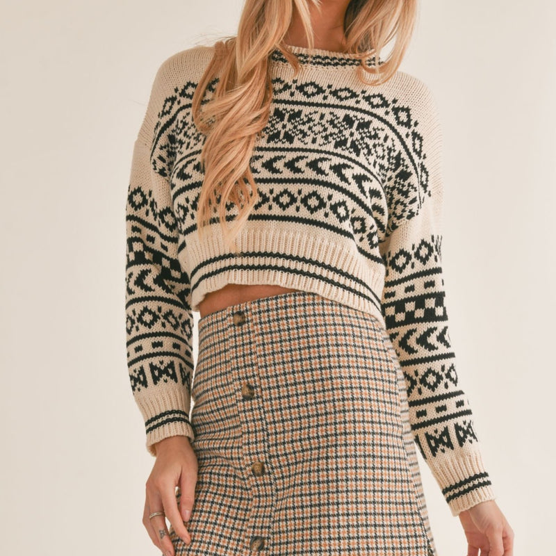 front view of the about time sweater. shows the cute pattern throughout. also shows the crop length of the sweater, the crew neckline, the dropped shoulders and the ribbed detail on the cuffs, hem and neckline.