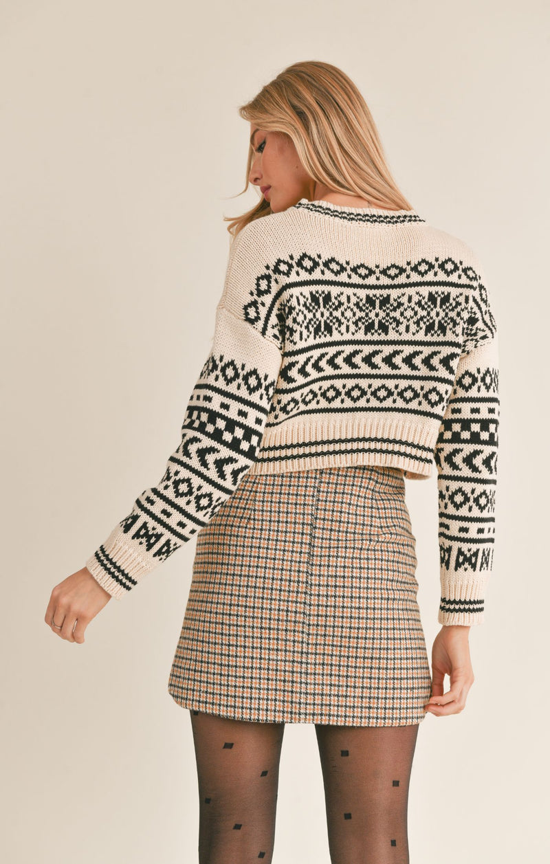 back view of the model wearing the about time sweater. shows the drop shoulders. also shows the cute black pattern throughout and the ribbed detail on the cuffs, hem and neckline.