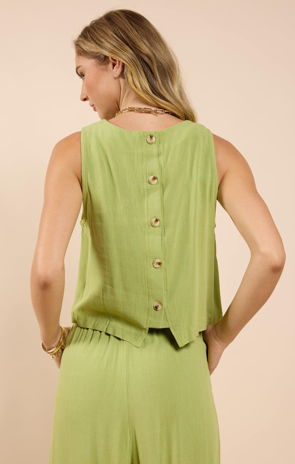 back view of the model wearing the sugarloaf linen tank. shows the back button detail. also shows the green color and that the back is slightly longer then the front. 
