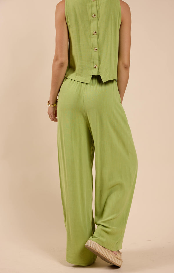 back view of the model wearing the sugarloaf elastic waist pants. shows the green color. also shows the pull on style and the wide leg. 