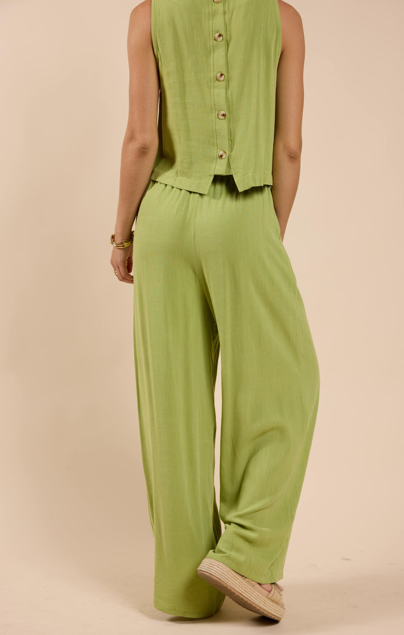 back view of the model wearing the sugarloaf elastic waist pants. shows the green color. also shows the pull on style and the wide leg. 