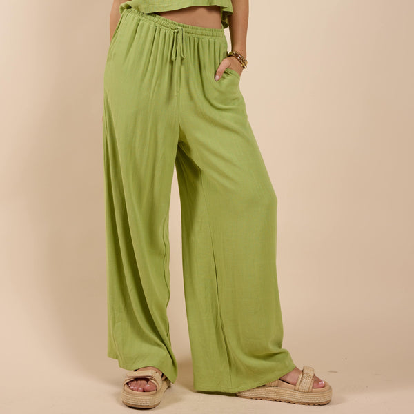 front view of the model wearing the sugarloaf elastic waist pant. shows the drawstring. also shows the side pockets, the green color and the wide leg. 