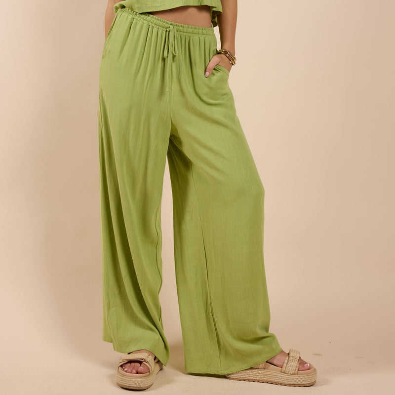 front view of the model wearing the sugarloaf elastic waist pant. shows the drawstring. also shows the side pockets, the green color and the wide leg. 