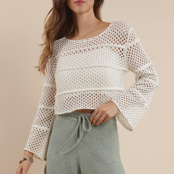 front view of the model wearing the poppy crochet bell sleeve sweater. shows the scoop neckline. also shows the crochet detailing the bell sleeves, and the cropped length. 