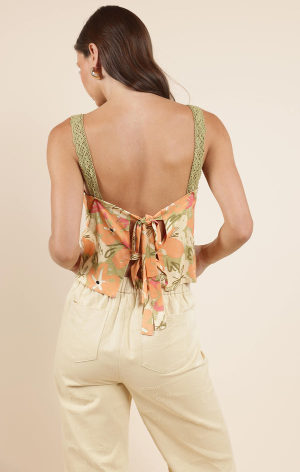 back view of the model wearing the aperitivo lacey back tied top. shows the tie back. also shows the lace straps, the low back and the floral print. 