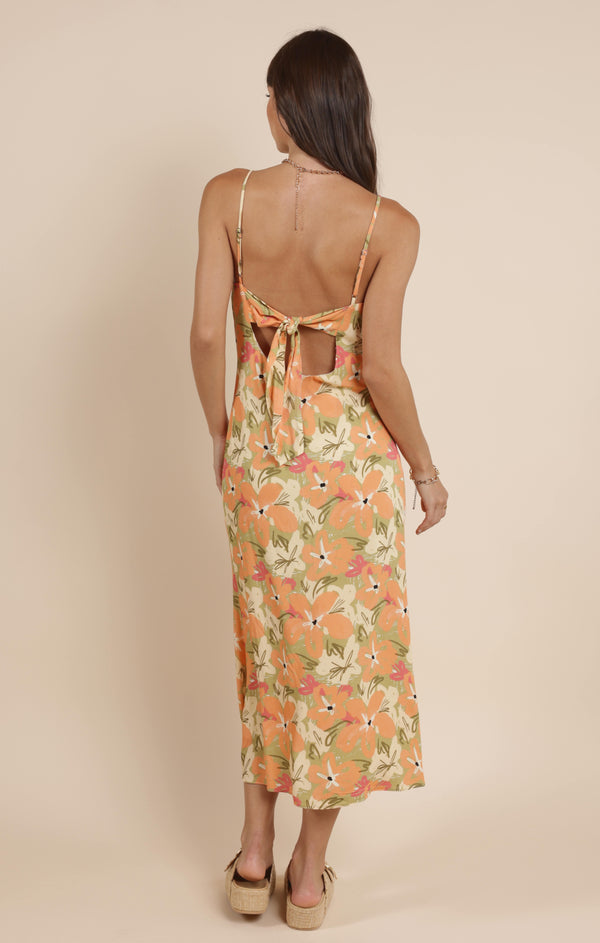 back view of the model wearing the aperitivo midi dress. shows the adjustable straps. also shows the tie back detailing, the midi length and the floral print. 