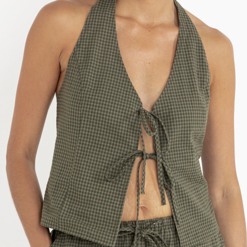front view of the model wearing the Louise halter checkered top. shows the halter neck. also shows the tie front closure, the v neckline, and the green checkered pattern. 