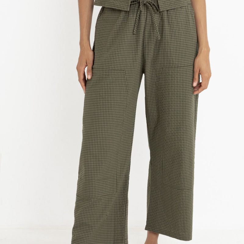 front view of the model wearing the louise check pants. shows the drawstring waistband. also shows the front patch pockets, the high rise and the olive checkered print. 