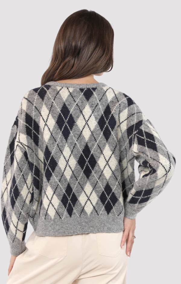 Person wearing a gray argyle sweater on a light gray background