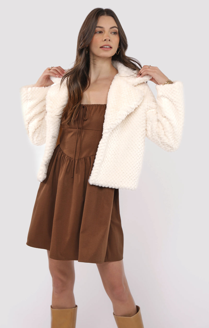 Woman wearing a brown dress with a white fur coat on a white background