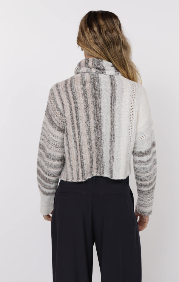 Person wearing a striped sweater and black pants on a white background
