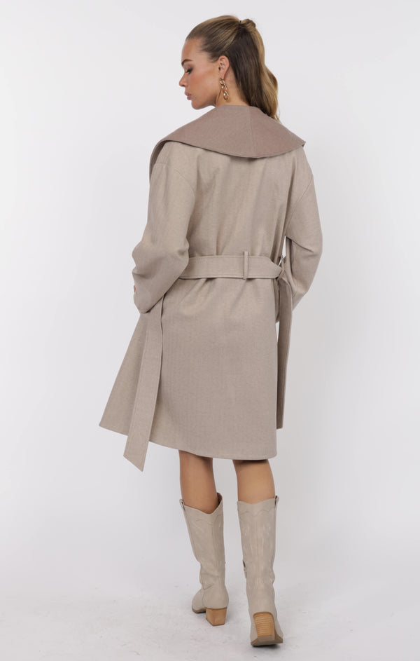 Woman wearing a beige trench coat and knee-high boots on a white background