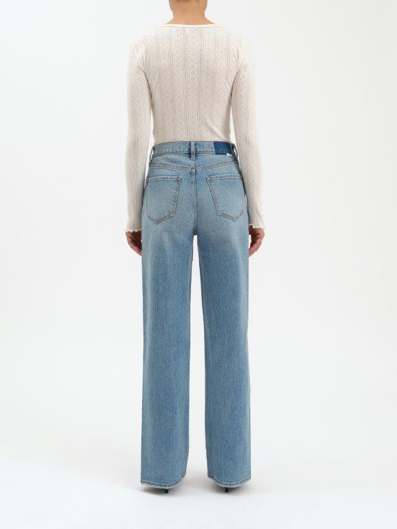 Person wearing light blue jeans and a cream sweater on a white background