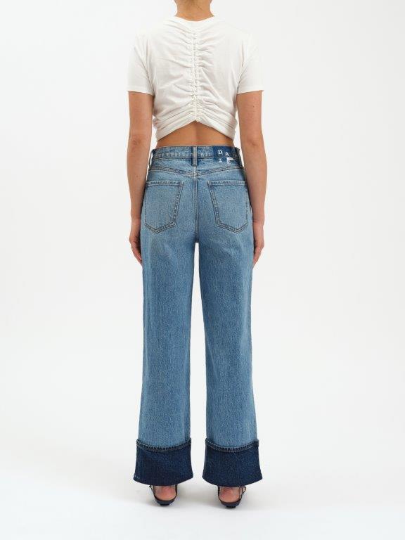 Person wearing blue wide-leg jeans with a white top on a white background