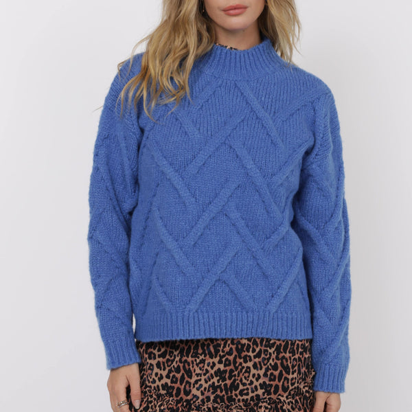 Woman wearing a blue knitted sweater and leopard print skirt on a white background