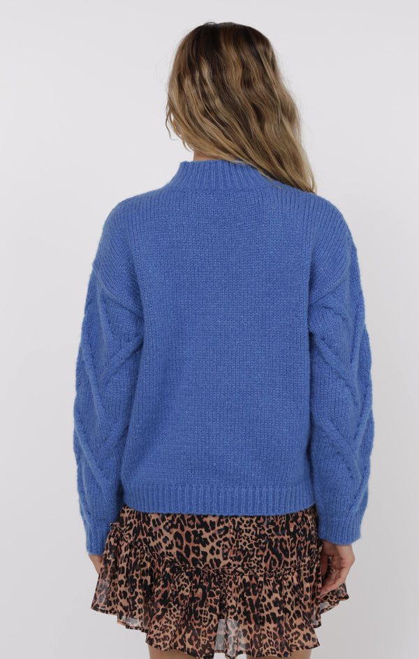 Person wearing a blue sweater and leopard print skirt on a white background