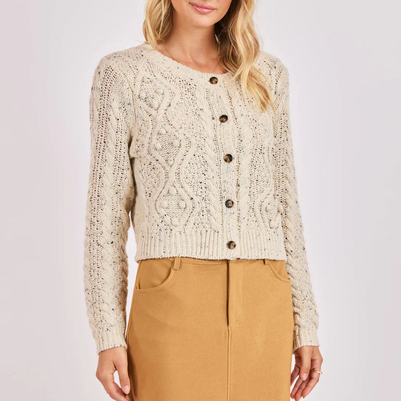 Woman wearing a beige knitted cardigan and tan skirt on a white background