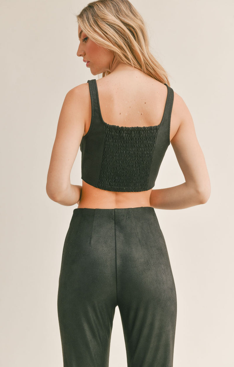 Back view of model wearing top. Shows the smocked backing. Also shows the crop fit of the top. 