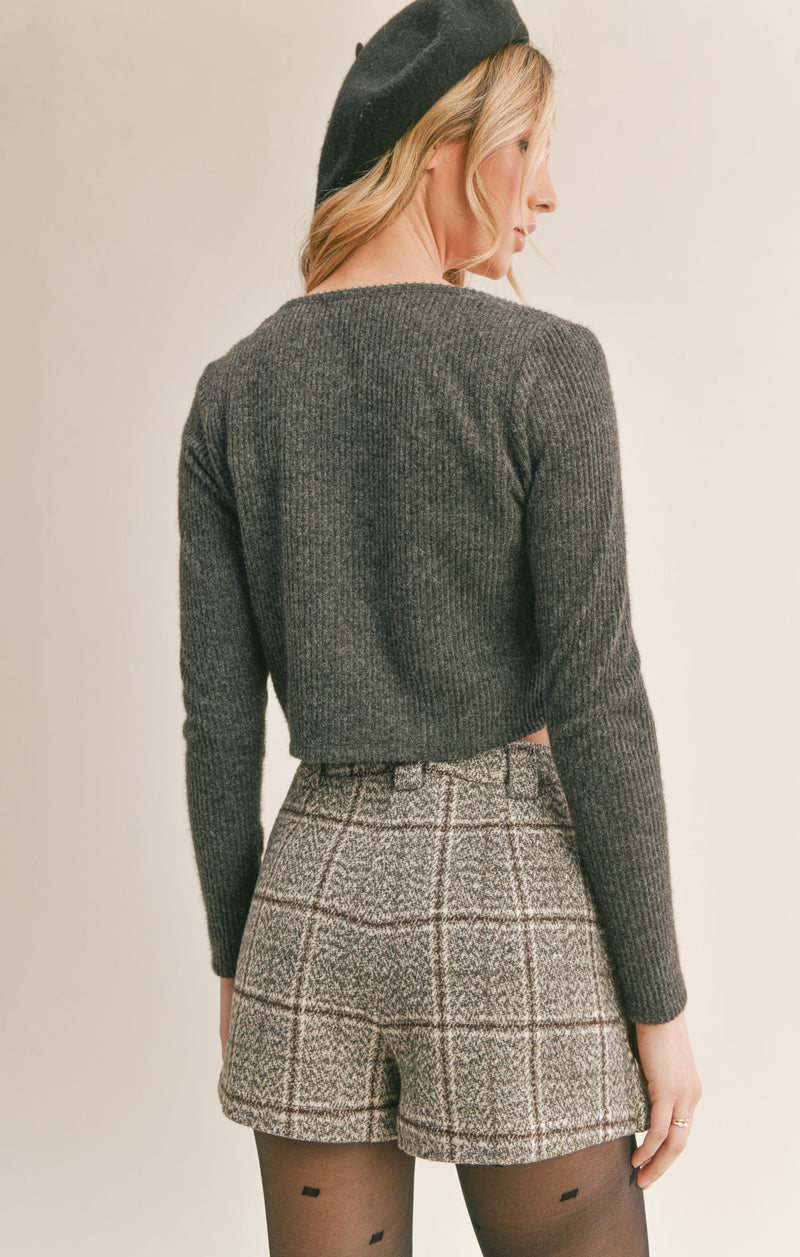 back view of model wearing cardigan. Shows the cropped fit. Also shows the ribbed detailing and the back shows its a tad but longer then the front. 