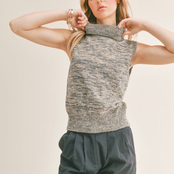 Front view of model wearing vest. Shows the turtleneck. Also shows the tighter fitting bottom and ribbed hem. It also shows that it is sleeveless. 