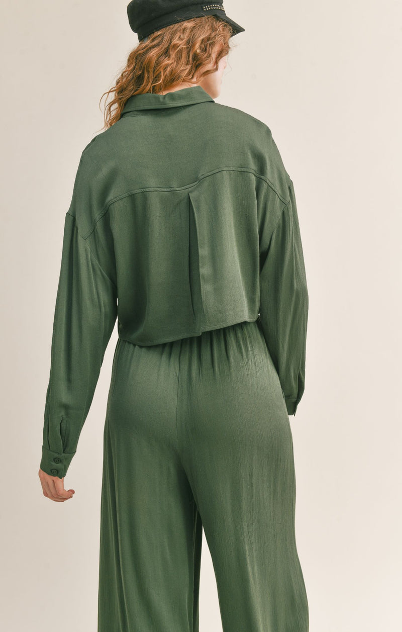 Back view of crop shirt. Shows the back pleat. Also shows the back seam throughout the back and button closure cuff.  