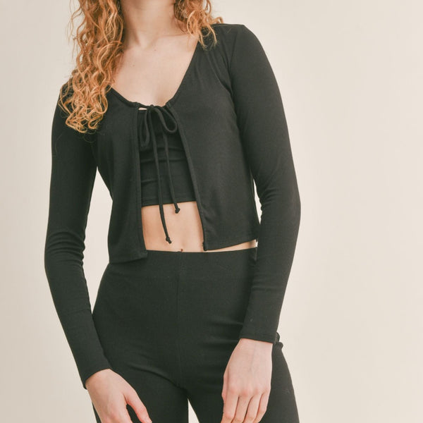 Front view of model wearing the cardigan. Shows the tie closure. Also shows the opening under the tie and the cropped fit.