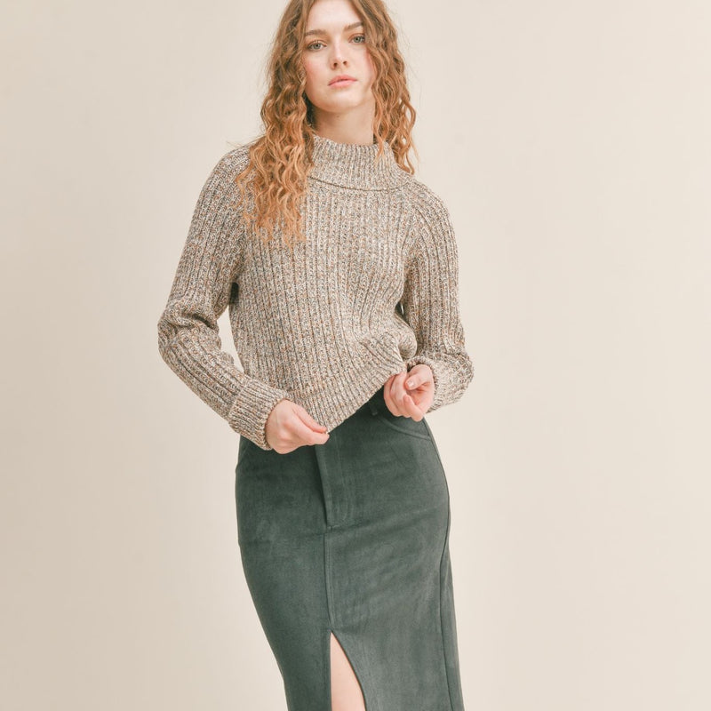 Front view of model wearing sweater. Shows the turtleneck . Also shows the folded cuffs and ribbed hem.