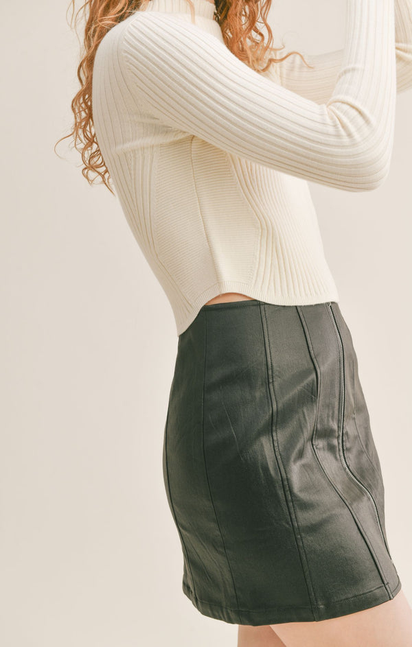 Side view of model wearing sweater. Shows the sides are non ribbed. Also shows that the hem goes up aliitle on the sides.