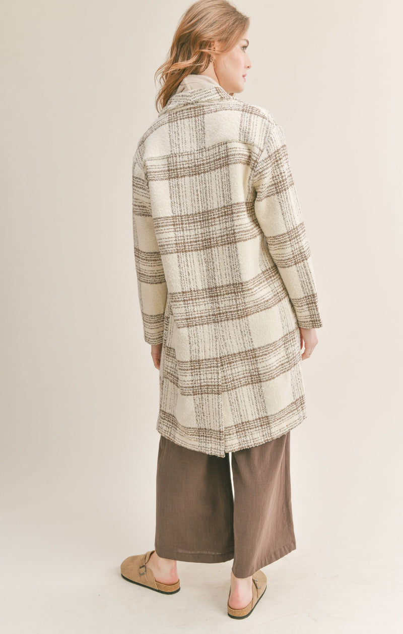 Back view of model wearing the jacket. Shows the knee length of the jacket. Also shows the back split hem. 