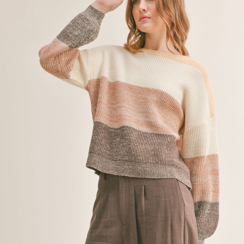 Front view of model wearing sweater. Shows the high neckline. Also shows the drop shoulder hem and the synched cuff. 