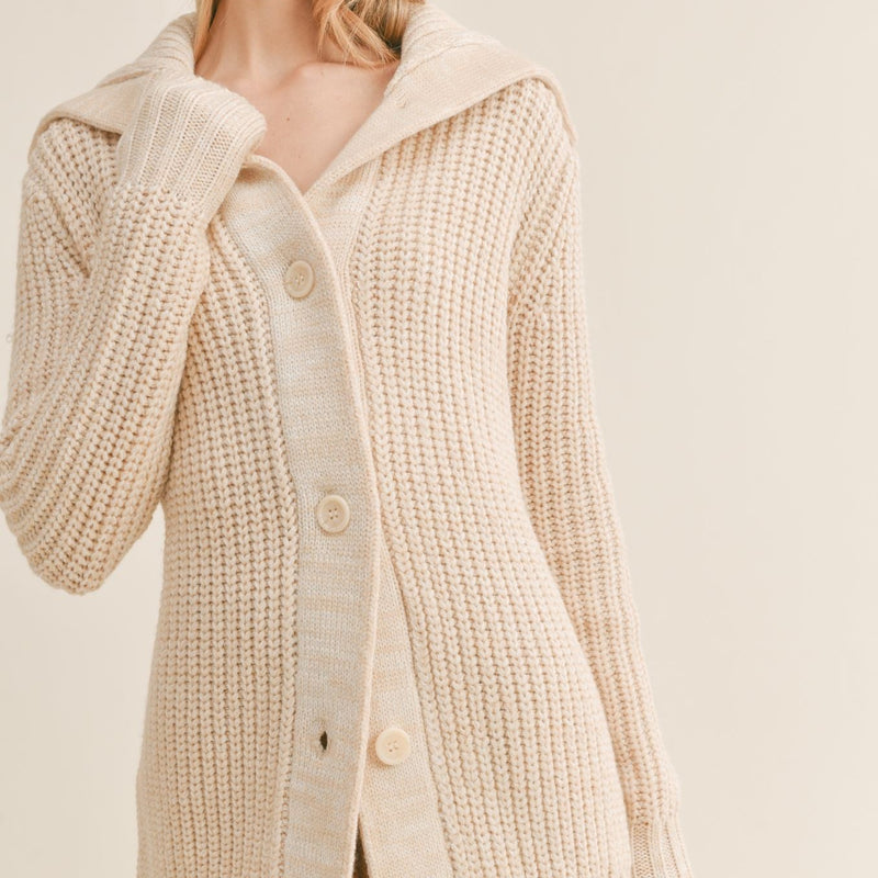Front view of model wearing cardigan. Shows the buttons closure. Also shows the wide collar and knit sweater material. 