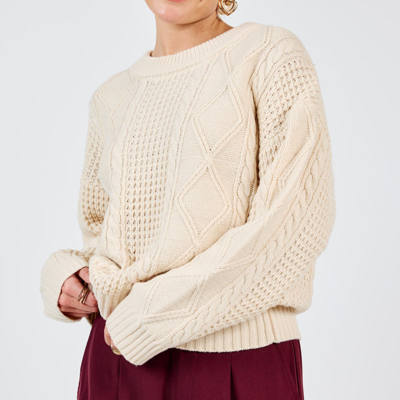 front view of the model wearing the teri cable crew neck sweater. shows the crew neckline. also shows the dropped shoulders, and the cable knit detailing. 