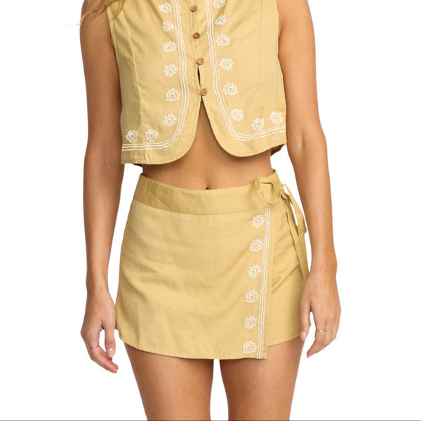 Woman wearing a yellow sleeveless top and skirt set on a white background