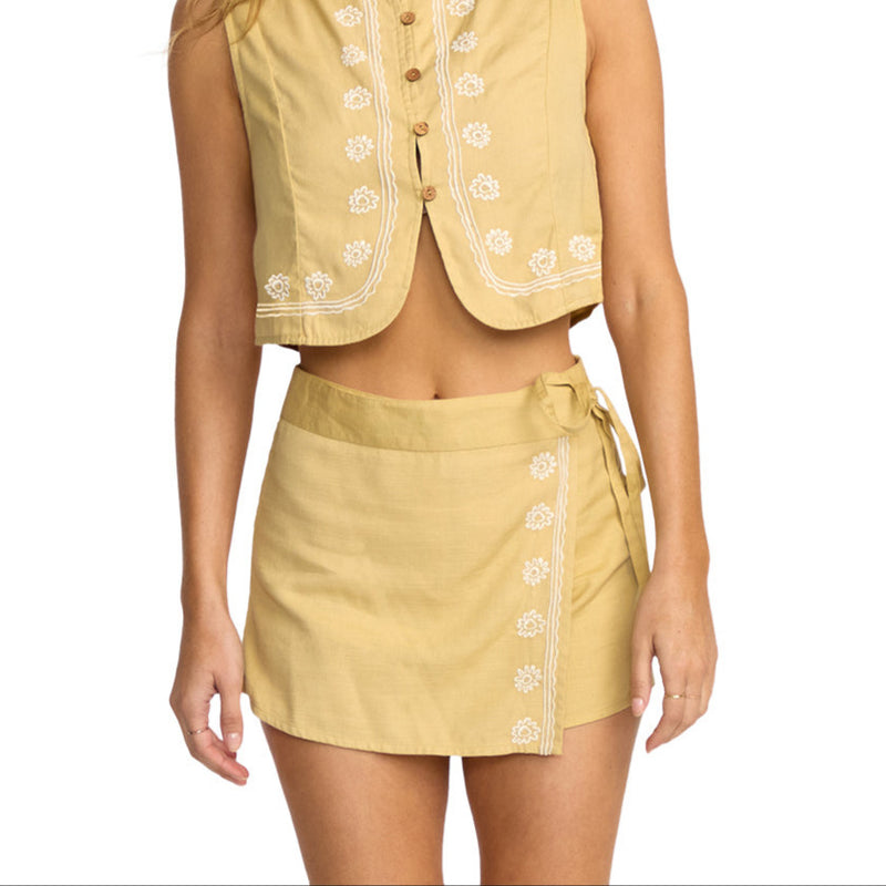 Woman wearing a yellow sleeveless top and skirt set on a white background
