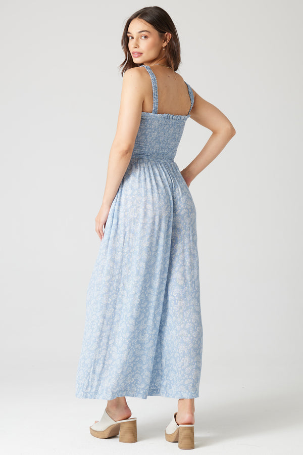 back view of the model wearing the daisy jumpsuit. shows the wide legs. also shows the smocked bodice, the elastic straps and waist. 