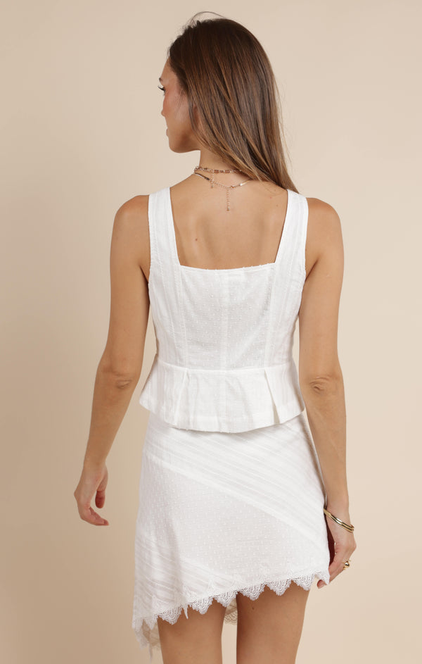 back view of the model wearing the morning dew embroidered peplum vest. shows the back square neckline. also shows the peplum style, straps and the white color. 