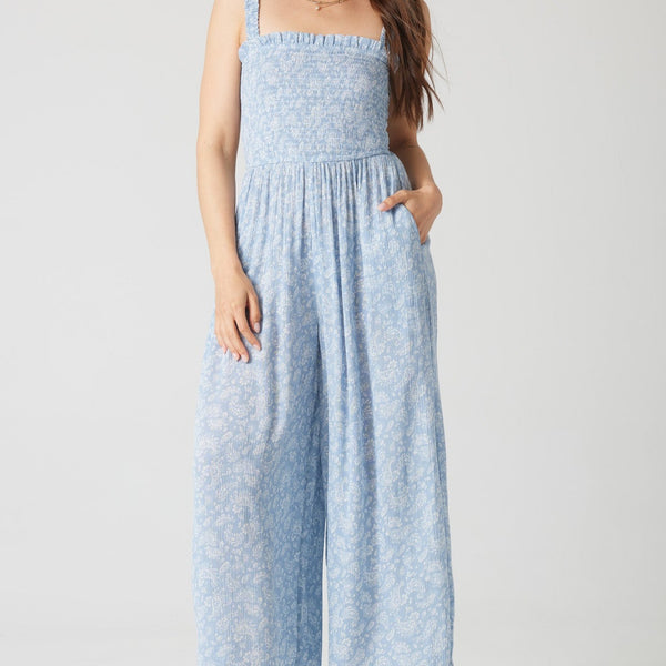 front view of the model wearing the daisy jumpsuit. shows the smocked bodice. also shows the side pockets, the elastic waistband and the elastic straps. 