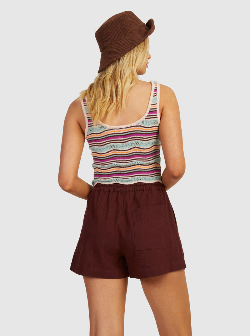 back view of model in tank. shows the scoop back, fixed straps and scalloped hemline. hits model at top of her shorts waistband.