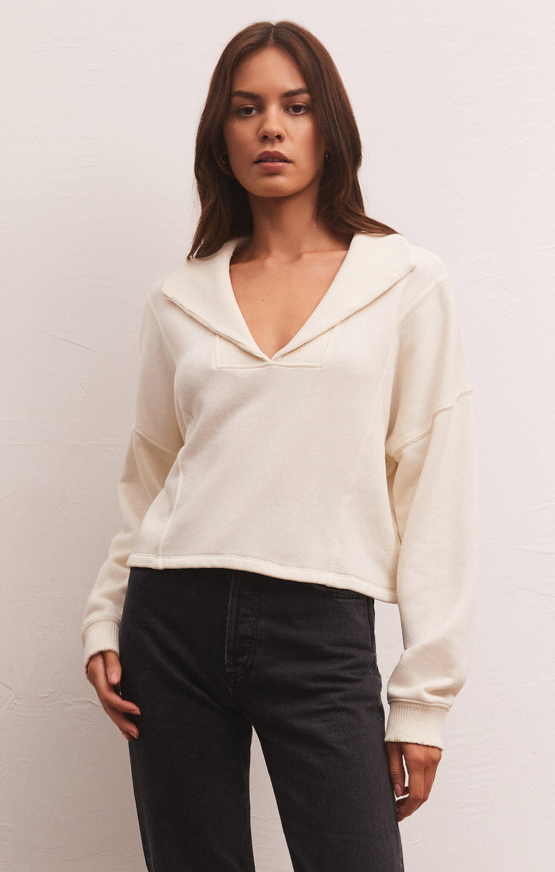 shows front view of model in sweatshirt. shows the slplit neck, long sleeves with dropped shoulders and exposed seams on the front.