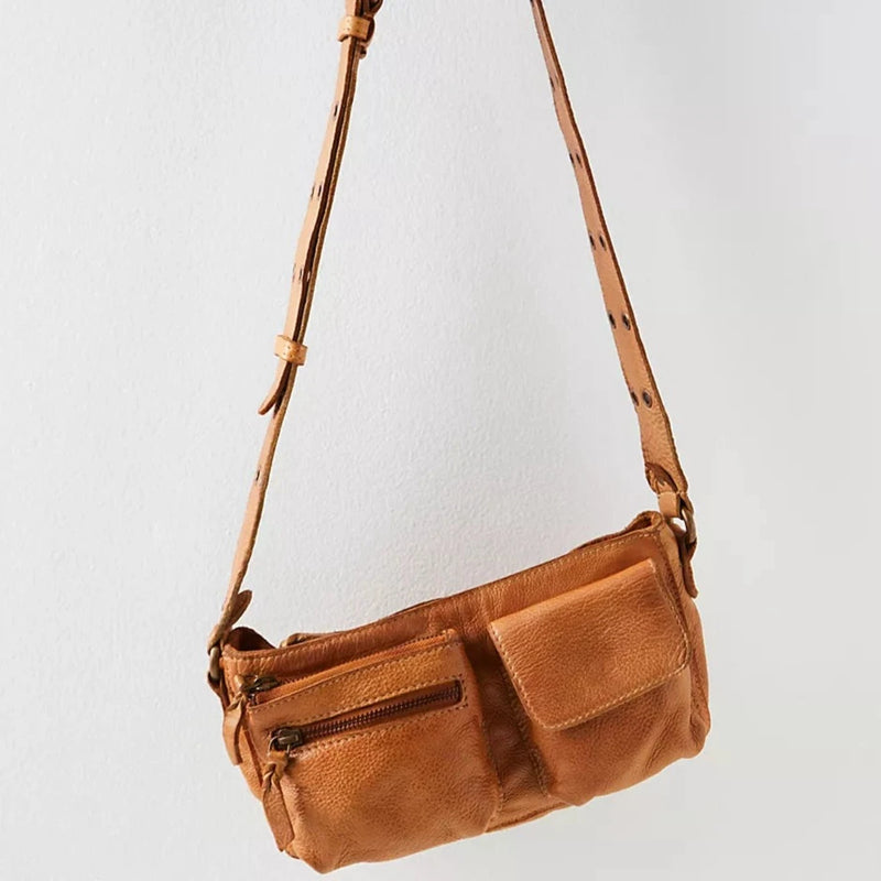 front view of the wade leather sling. shows adjustable straps with garments, also shows the one zipper pouch and the one fold over closure pouch. 